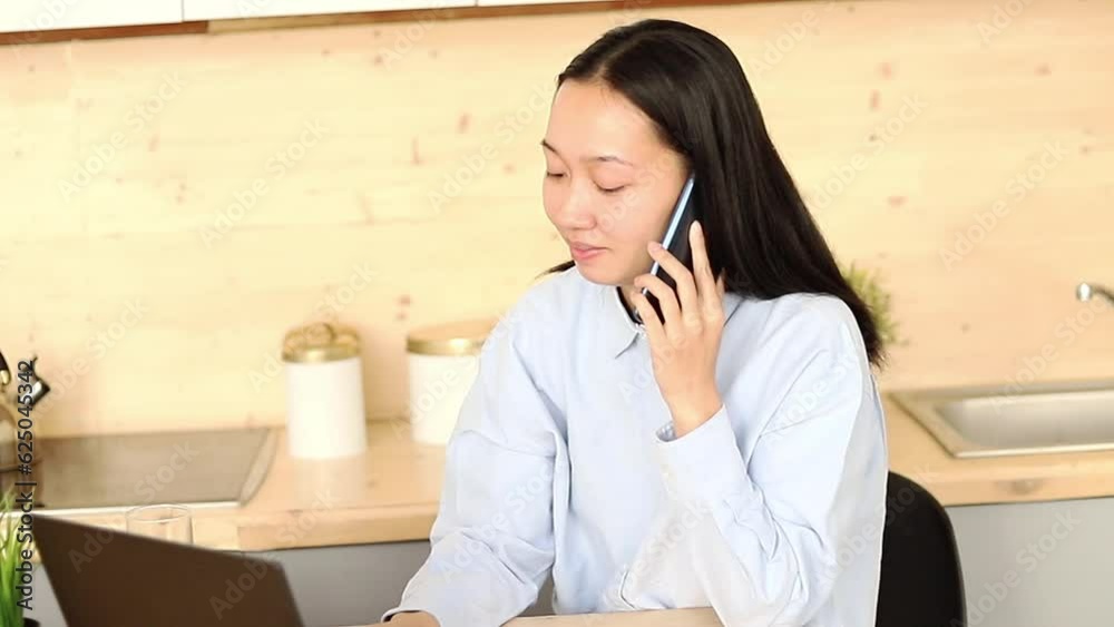 Asian girl works freelance remotely at home in the kitchen sitting at a laptop Asian girl works freelance remotely at home in the kitchen sitting at a laptop