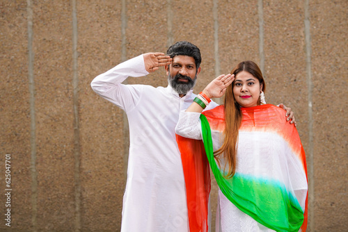 Indian couple in traditional wear and giving salute together.