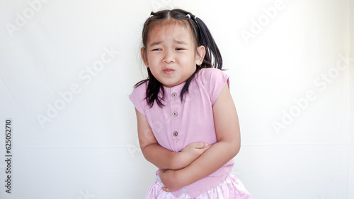 Studio portrait of sick child girl touches herself stomach and looks unhappy.