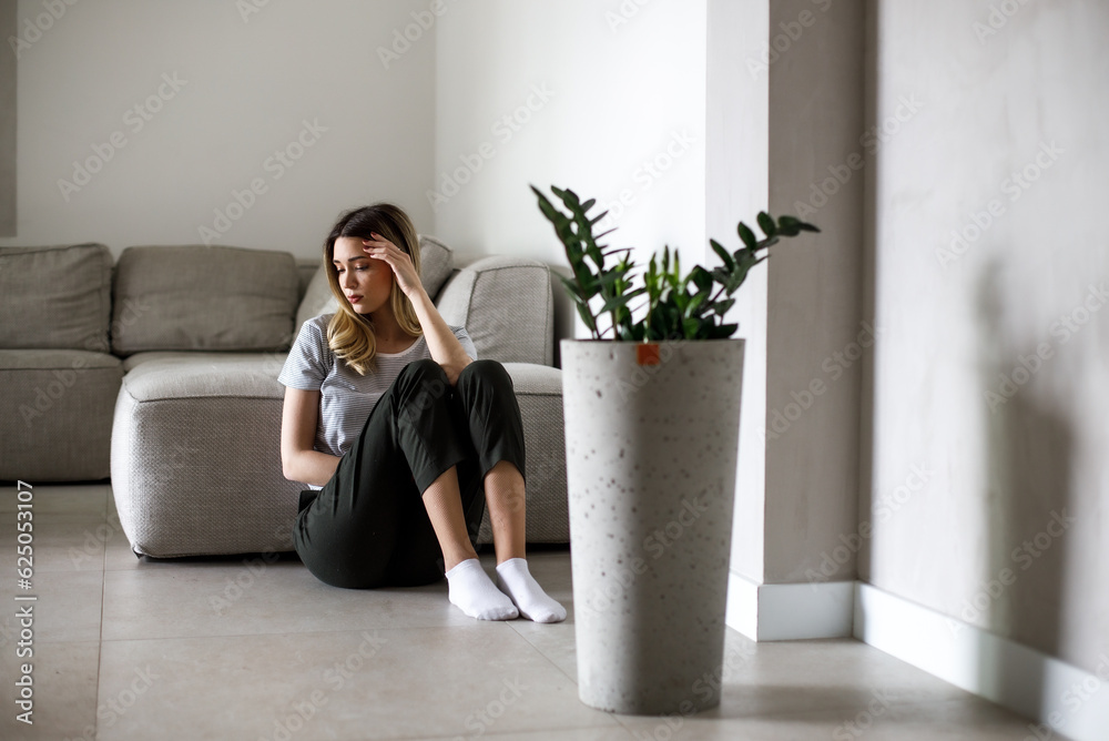 Sad woman sitting on couch alone at home Sad woman sitting on couch alone at home