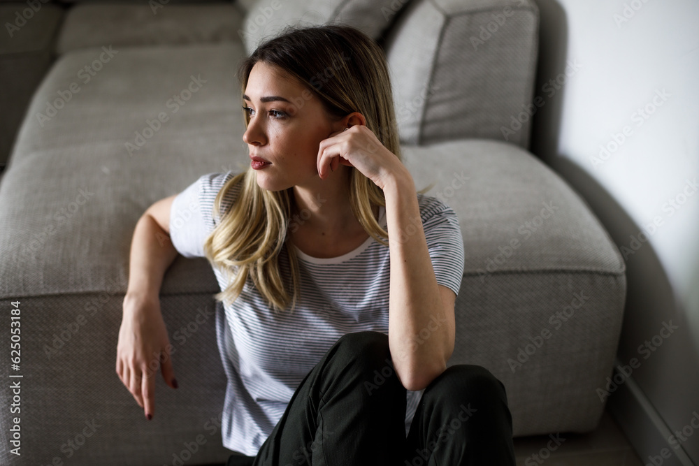 Obraz premium Sad woman sitting on couch alone at home