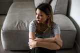 Sad woman sitting on couch alone at home