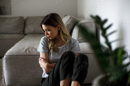 Sad woman sitting on couch alone at home