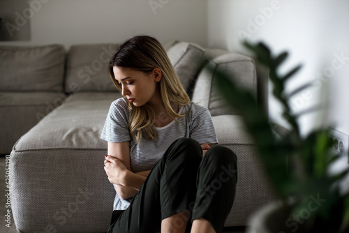 Sad woman sitting on couch alone at home photo