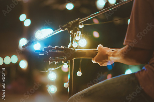 Musical and enjoyment concepts. Rear view of the man sitting play acoustic guitar on the outdoor concert with a microphone stand in the front.
