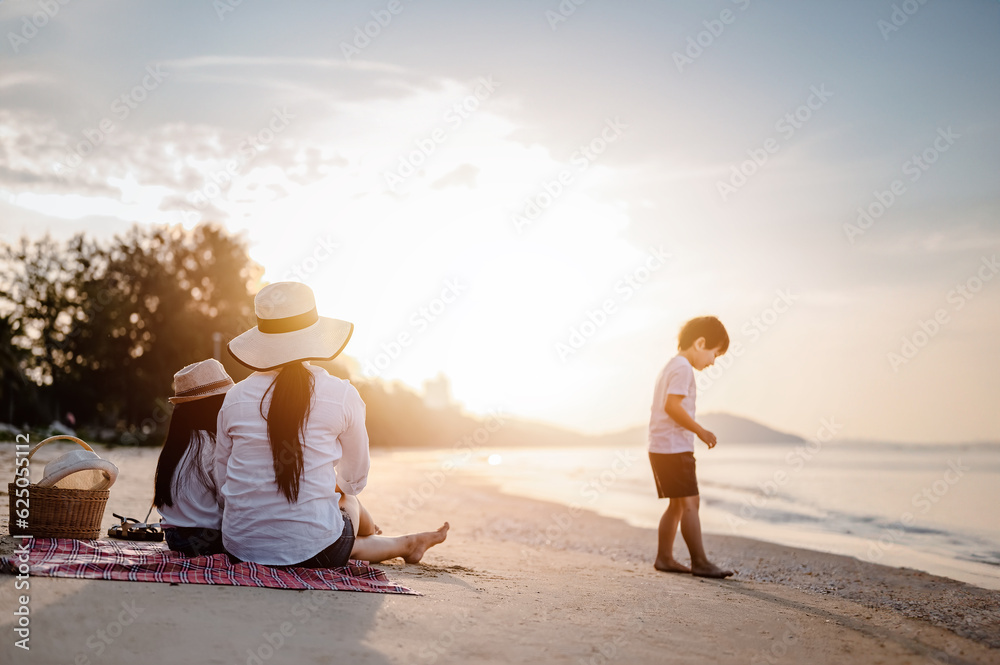 Holiday Family on the beach in summer, Travel, vacation and lifestyle concepts. Happy asian family together on the beach in holiday. Parent and baby sitting enjoying the sunset on the beach.