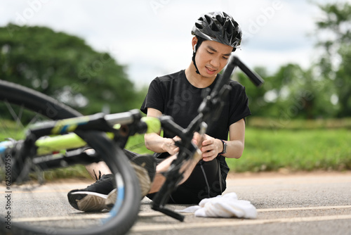 Bicycle accident. Young cyclist having an accident, falling down from bicycle and injured his knee