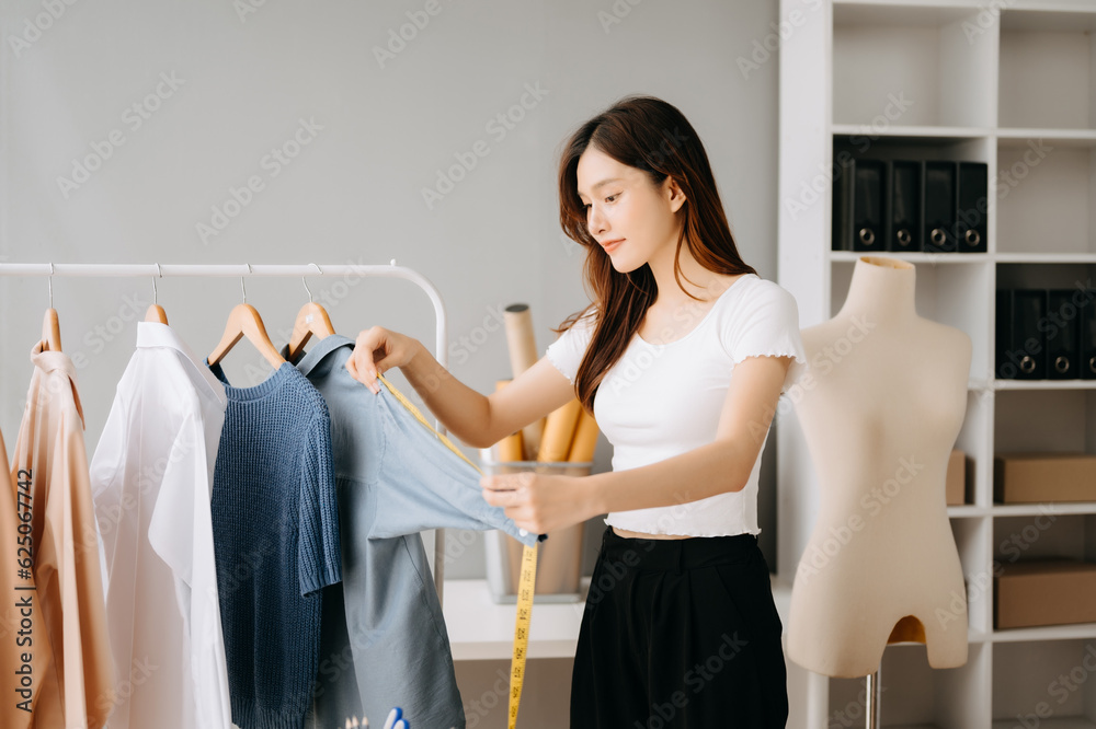 Asian tailor woman working on clothes in tailoring atelier. beautiful young female fashion designer smile and after success in modern studio Asian tailor woman working on clothes in tailoring atelier. beautiful young female fashion designer smile and after success in modern studio