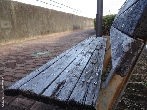 Close-up from the side of an old wooden bench on the street