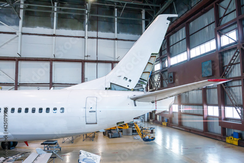 The back of a passenger airplane under maintenance in the hangar. Checking mechanical systems for flight operations