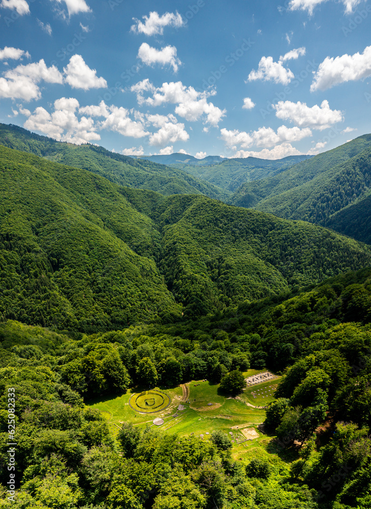 Aerial view over Sarmizegetusa Fortress in Romania. Photo from above during a beautiful sunny summer day. This historical fortress is surrounded by forests in Orastiei Mountains. Romania landmark.