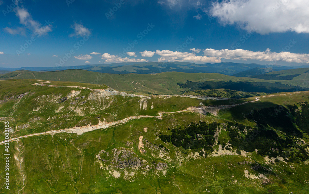 Beautiful roads of Romania. Aerial photo with Transalpina road on top of the mountains with big clouds above. Curved waving road.