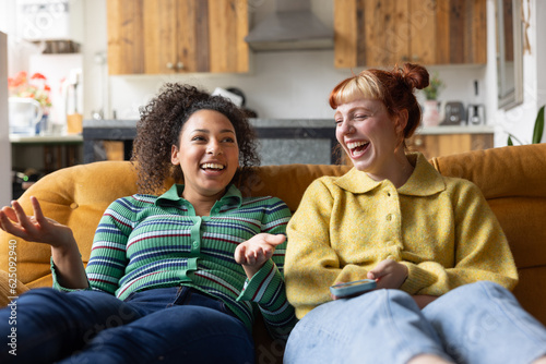 Two young adult friends laughing together in a shared loft apartment