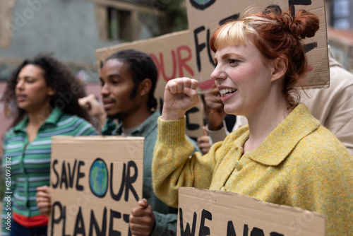 Young adult female protester raising her fist up at a climate change protest photo