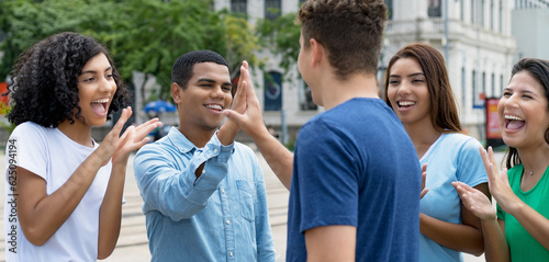 Happy multiethnic team of young adults give high five to friend photo