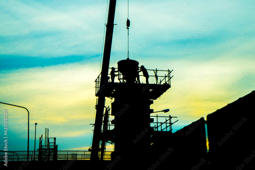 Construction worker working on a construction site. Silhouette of worker team on building site, construction site at sunset in evening time