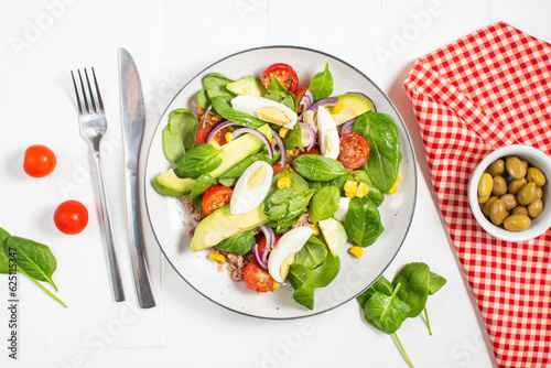 Tuna salad - tuna, avocado, hard boiled eggs, cherry tomatoes, lettuce and onion on wooden table