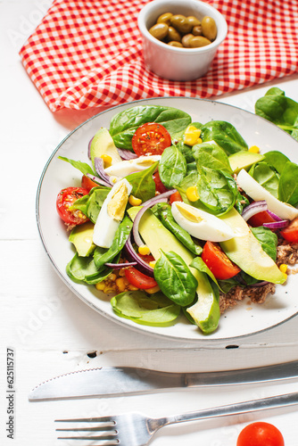 Tuna salad - tuna, avocado, hard boiled eggs, cherry tomatoes, lettuce and onion on wooden table. Healthy