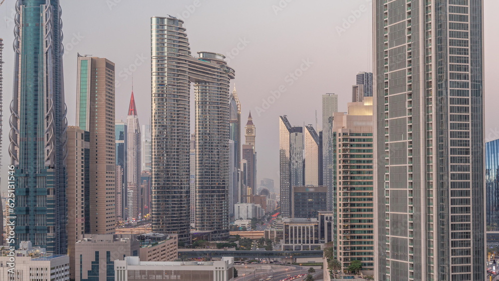 Obraz premium Many towers and skyscrapers with traffic on streets in Dubai Downtown and financial district day to night timelapse.