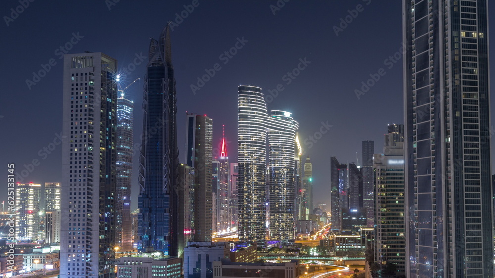 Many towers and skyscrapers with traffic on streets in Dubai Downtown and financial district all night timelapse.