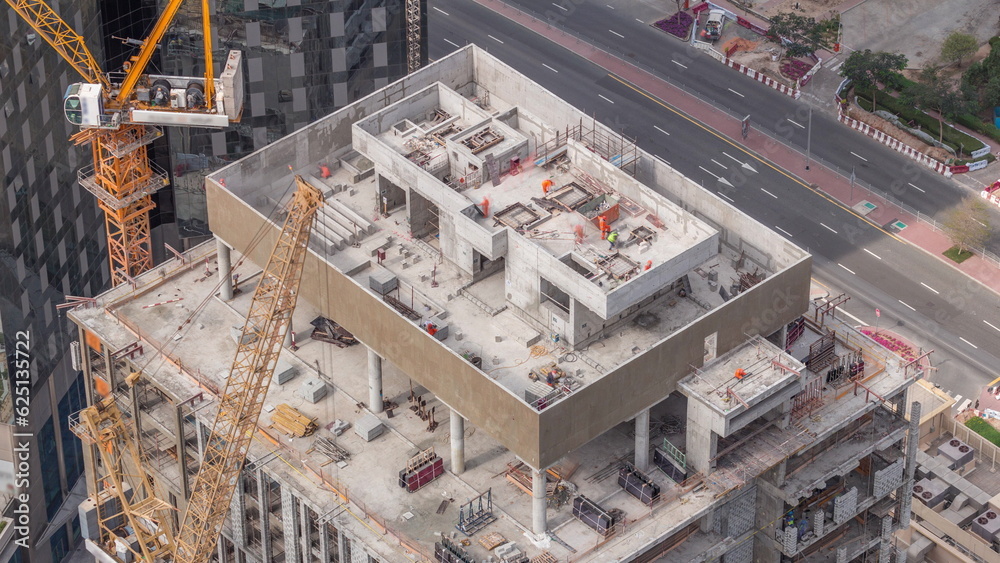 Tower cranes working on the construction site of new skyscraper high-rise building aerial timelapse. Dubai