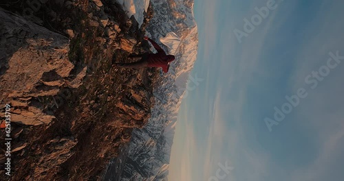 Powerful shot of a man running to the mountain peak with white flag in hands. Male emotionally runs with white flag, raises it high and waves. Concept of peace and freedom. Vertiacal shot photo