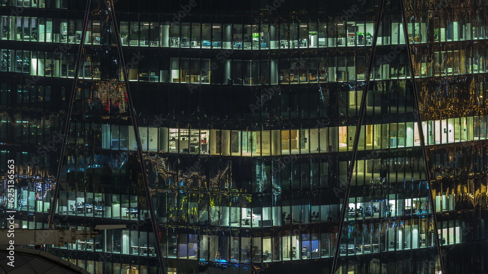 Frontal view of night facade of building with a lot of windows with light timelapse.