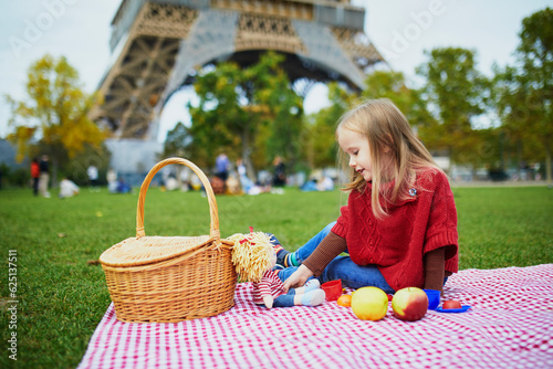 Adorable preschooler girl having picnic near the Eiffel tower in Paris, France photo