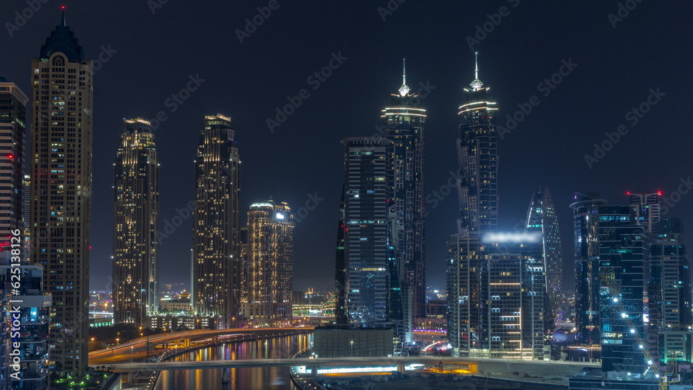 Cityscape with skyscrapers of Dubai Business Bay and water canal aerial all night timelapse.