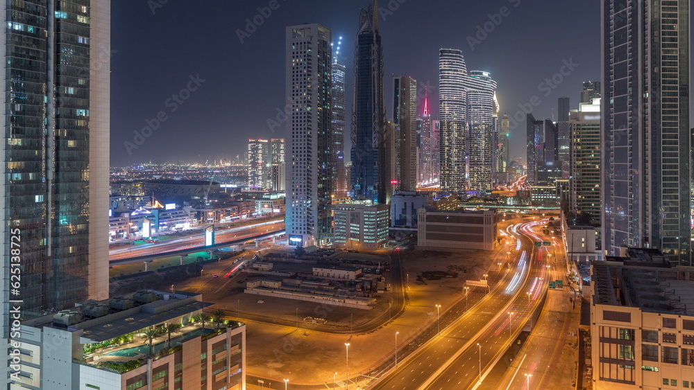 Many towers and skyscrapers with traffic on streets in Dubai Downtown and financial district night timelapse.