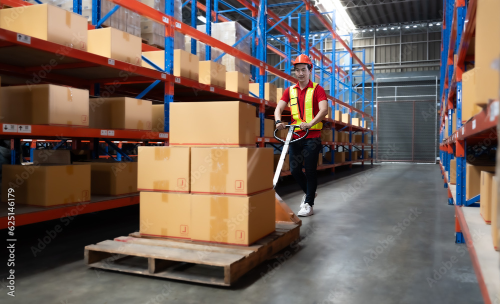 Young man pulling hand pallet truck loading package boxes stacked in shipping warehouse. Asian worker moving merchandise from storage shelf by hand lift pallet jack. Delivery goods, cargo transport.