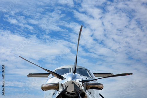 The nose of a Pilatus as seen from the front looking up.  Blue sky and cirrus clouds in the background. 