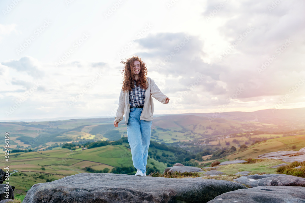 Naklejka premium woman traveler in a white jacket traveling mountains in Peak District and reaching the destination. Local tourism lifestyle concept.