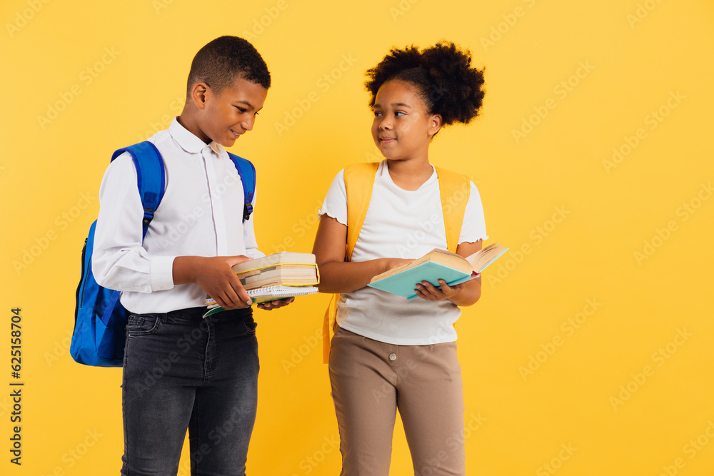 Happy african american schoolgirl and schoolboy holding books on yellow background, copy space. Happy african american schoolgirl and schoolboy holding books on yellow background, copy space.