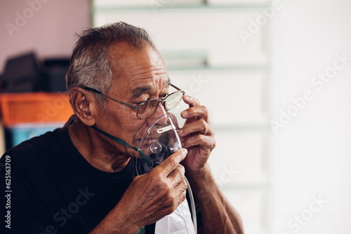 Elderly Senior Man wear oxygen inhaler device for helping breath respiratory. Patient use portable oxygen at home. Patients with respiratory disorders. portable oxygen concentrator or oxygen generator photo