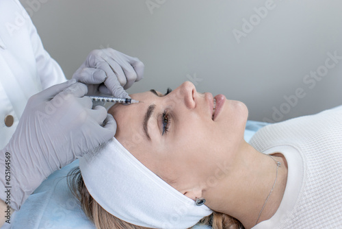 A dermatologist cleanses the skin on a young woman's face with an instrument