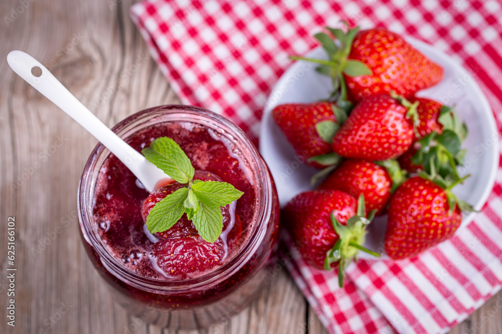 Homemade delicious strawberry jam and strawberry on a rustic wooden table Homemade delicious strawberry jam and strawberry on a rustic wooden table