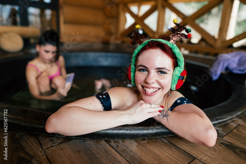 Young girls in bikinis bathing in an outdoor bathtub on winter holidays