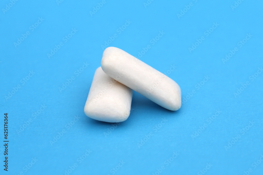 Two white chewing gum pads lie on a blue background.