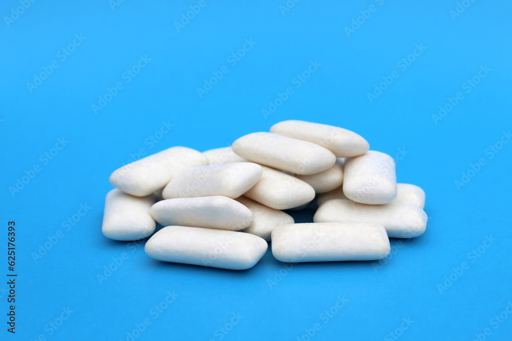 Many white chewing gum pads lie on a blue background.