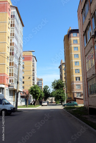 There are high-rise brick houses. Asphalt road. Summer.