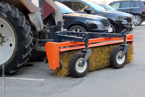 A tractor designed for cleaning the streets stands in the parking lot.