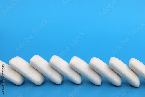 Many white chewing gums lie on a blue background.
