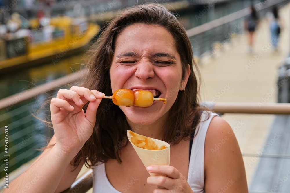 Tourist biting mitarashi dango, traditional Japanese rice dumplings ...