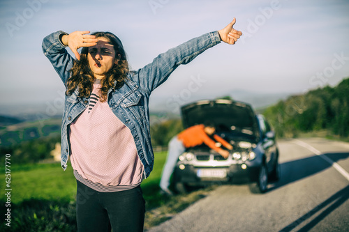 Young couples car broke down on the way. They hitchhike to find help. The hood is open and the engine of the car is broken