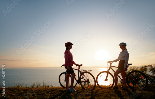 Εκτύπωση καμβά Two women with bicycles on the sea or lake shore