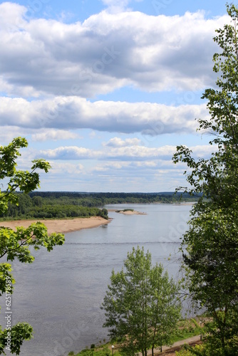 Beautiful view of a flowing river in summer with trees and fields.