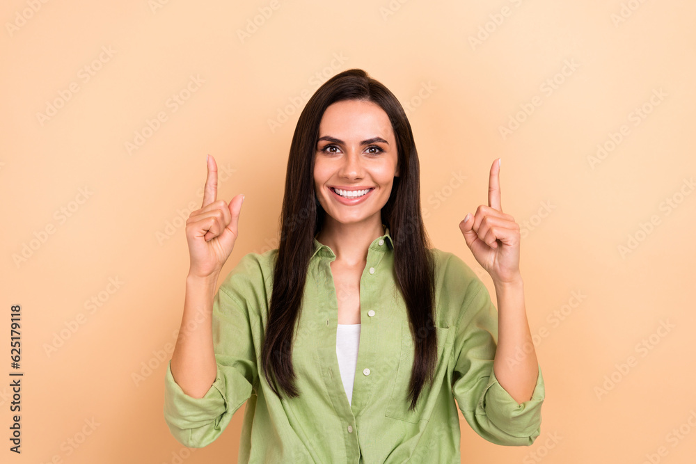 Photo of gorgeous cheerful person beaming smile direct fingers up above empty space proposition isolated on beige color background Photo of gorgeous cheerful person beaming smile direct fingers up above empty space proposition isolated on beige color background