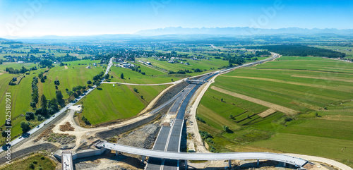 New fragment of highway under construction on Zakopianka road in Poland, from Krakow to Zakopane clearing Nowy Targ town, main place of traffic jams. State in July 2023. Tatra mountains in background
