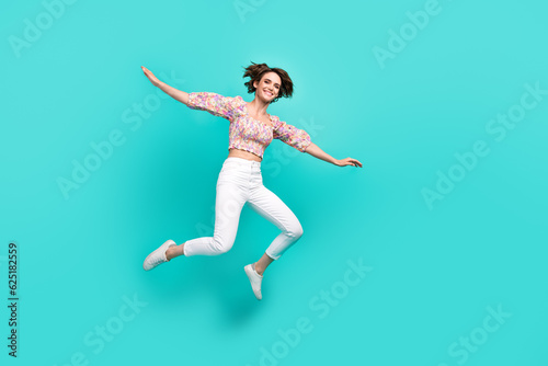 Full body photo of overjoyed cheerful lady jumping raise hands flying empty space isolated on teal color background